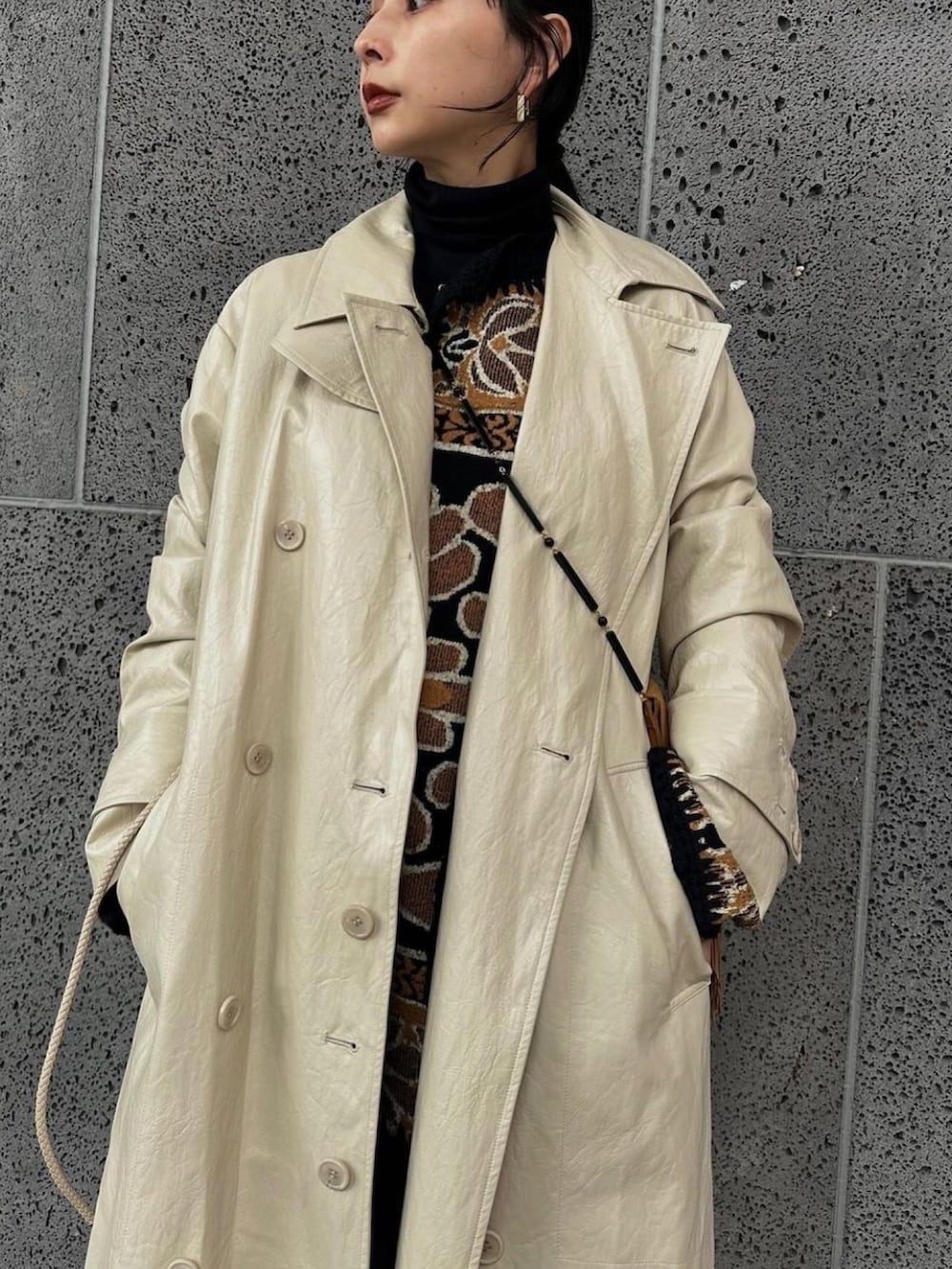 ホワイト系のトレンチコート、ベージュ系のベストを着用したレディースの秋コーディネートの3枚目の写真