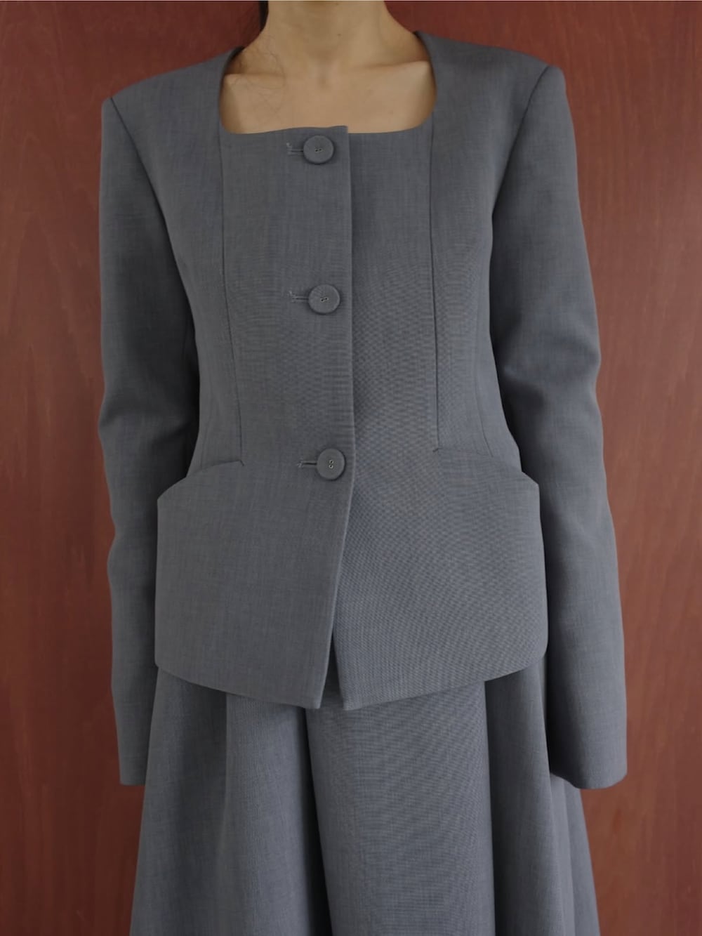 グレー系のスーツスカート、グレー系のノーカラージャケットを着用したレディースの冬コーディネートの3枚目の写真