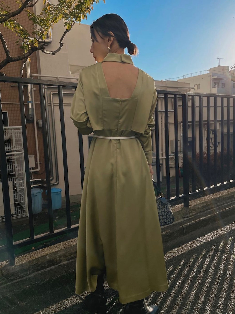 ブルー系のハンドバッグ、グリーン系のワンピース、ブラック系のブーツを着用したレディースの冬コーディネートの3枚目の写真