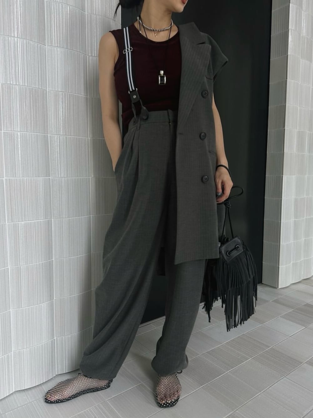 レッド系のタンクトップ、グレー系のベスト、ブラック系のショルダーバッグを着用したレディースの夏コーディネートの2枚目の写真