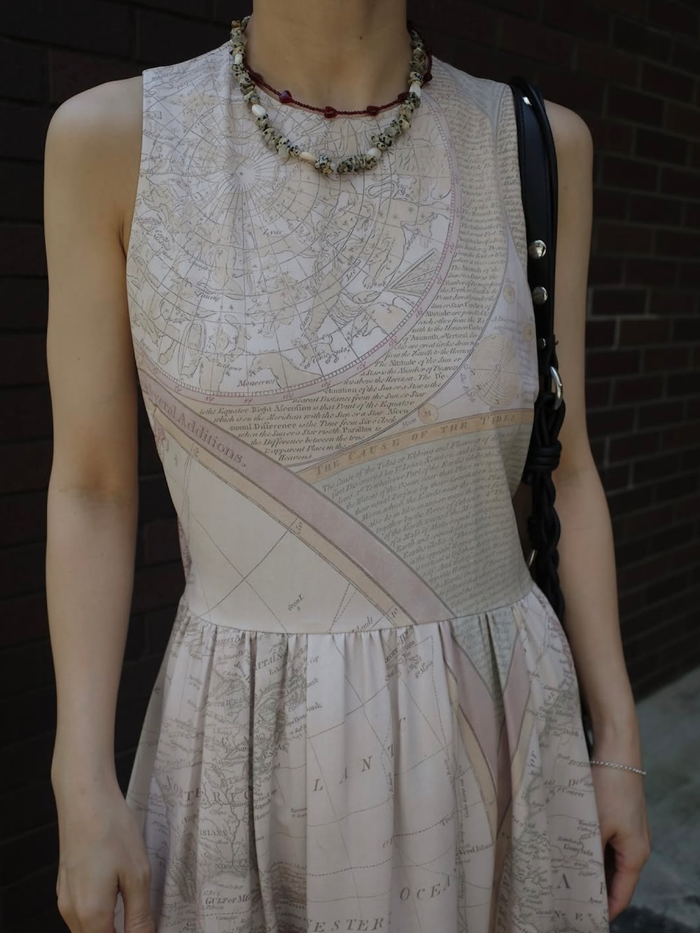 ベージュ系のワンピース、ホワイト系のサンダル、ブラック系のショルダーバッグを着用したレディースの夏コーディネートの2枚目の写真