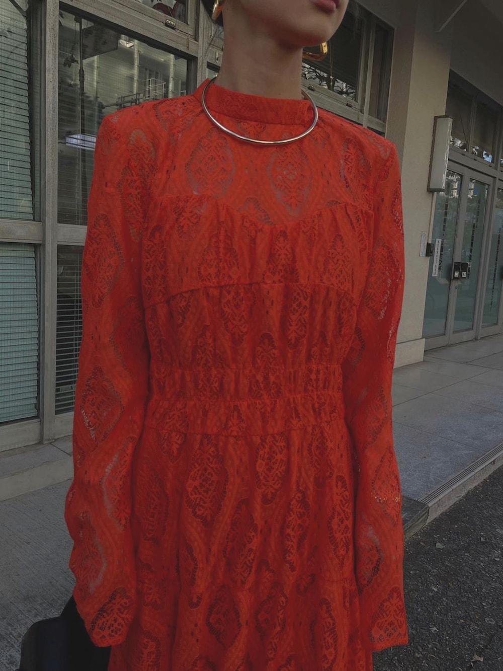 オレンジ系のワンピース、ゴールド系のチョーカーを着用したレディースの冬コーディネートの5枚目の写真