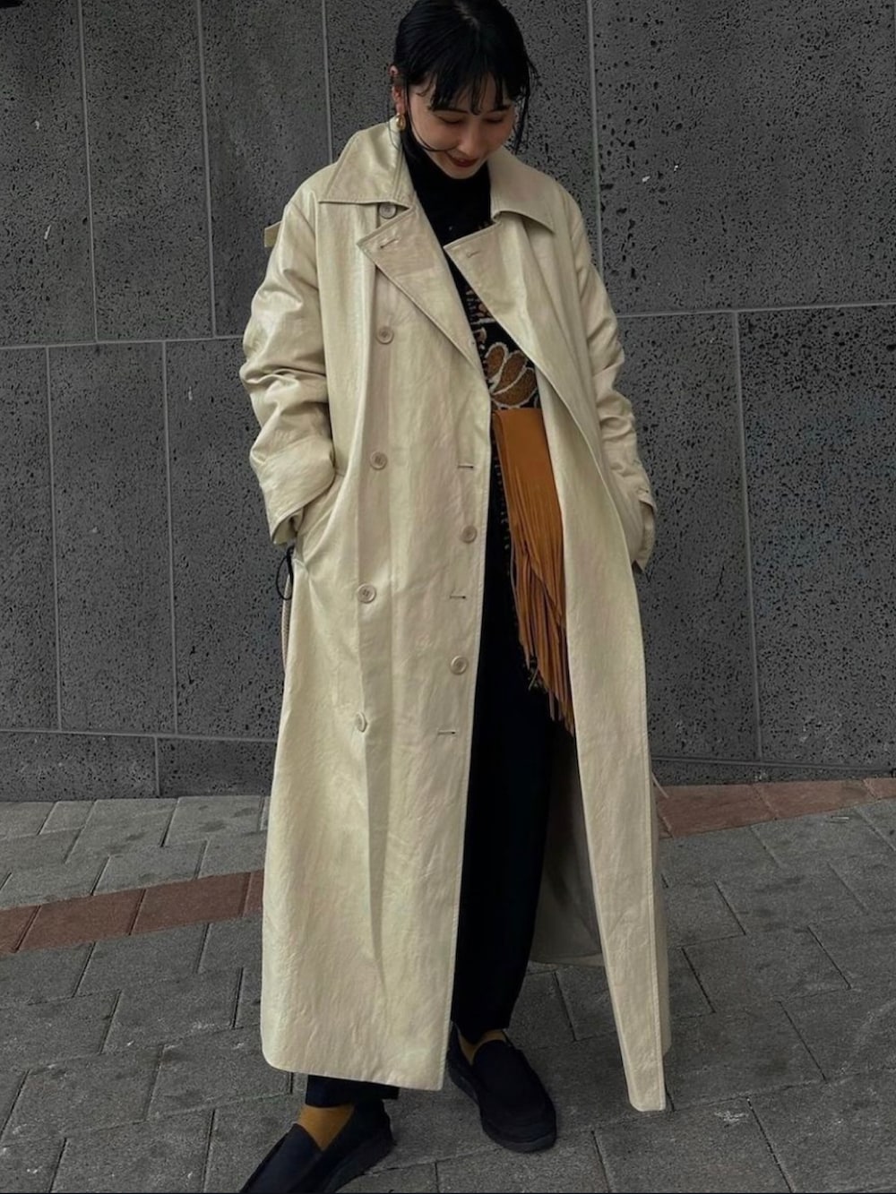 ホワイト系のトレンチコート、ベージュ系のベストを着用したレディースの秋コーディネートの5枚目の写真