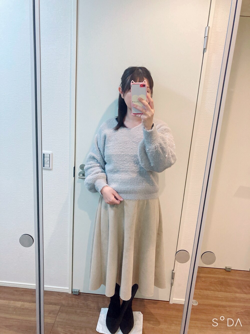 ブラック系のダウンジャケット/コート、グレー系のニット/セーター、ベージュ系のスカートを着用したレディースの冬コーディネートの2枚目の写真