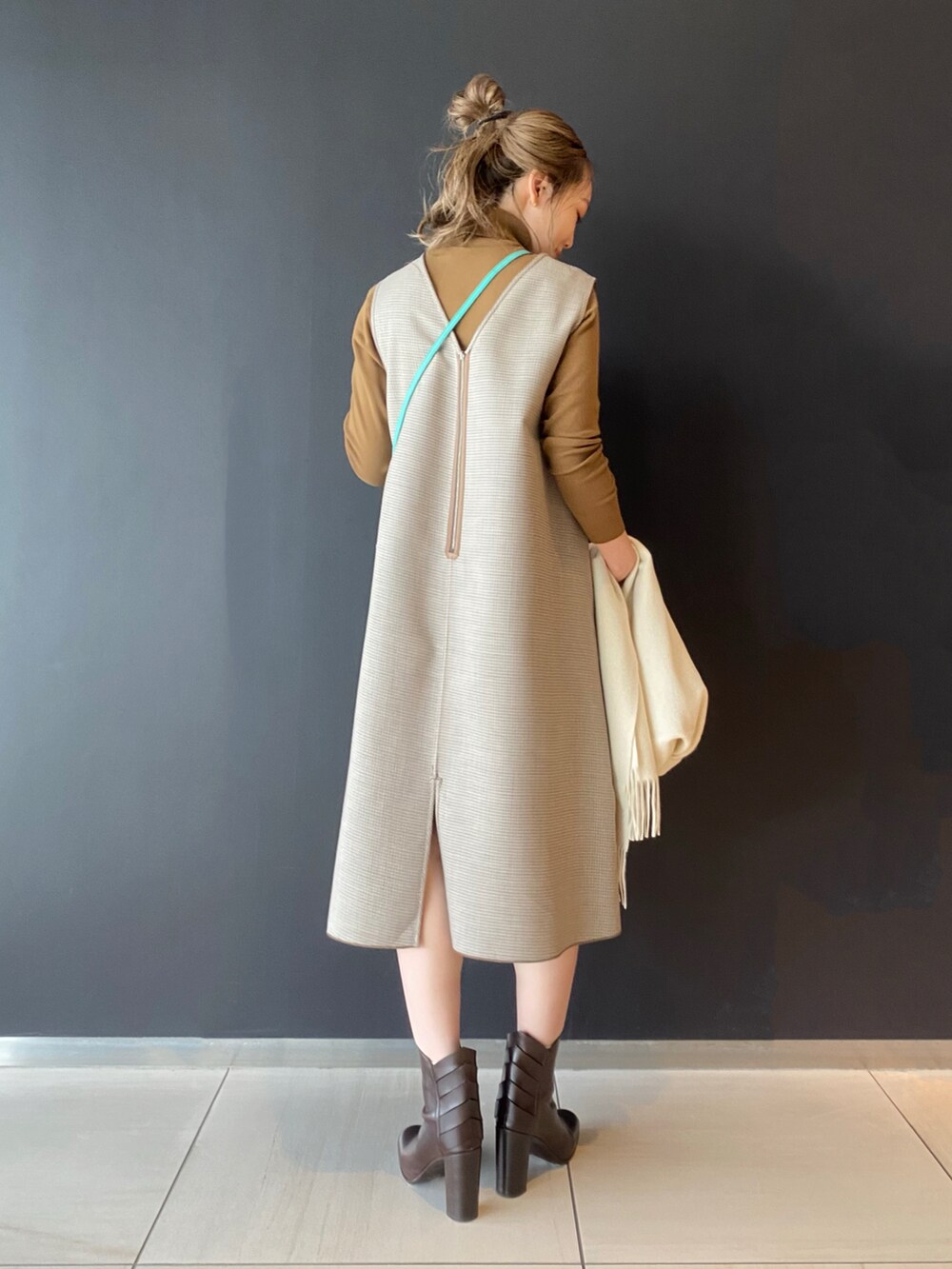 ブラウン系のワンピース、グリーン系のバッグ、ブラウン系のブーツを着用したレディースの秋コーディネートの2枚目の写真