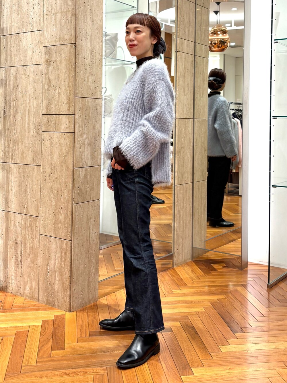 ブルー系のニット/セーター、ブラック系のブーツ、グレー系のヘアゴムを着用したレディースの冬コーディネートの2枚目の写真