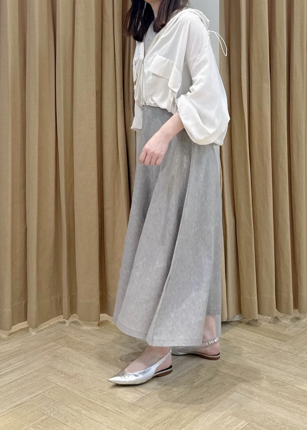 シルバー系のパンプス、ホワイト系のマウンテンパーカー、ベージュ系のワンピースを着用したレディースの春コーディネートの4枚目の写真