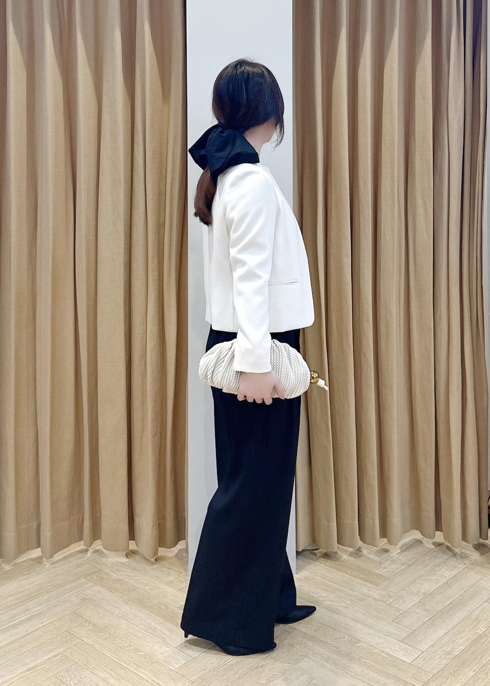 ブラック系のパンプス、ホワイト系のクラッチバッグ、ブラック系のニット/セーターを着用したレディースの冬コーディネートの2枚目の写真