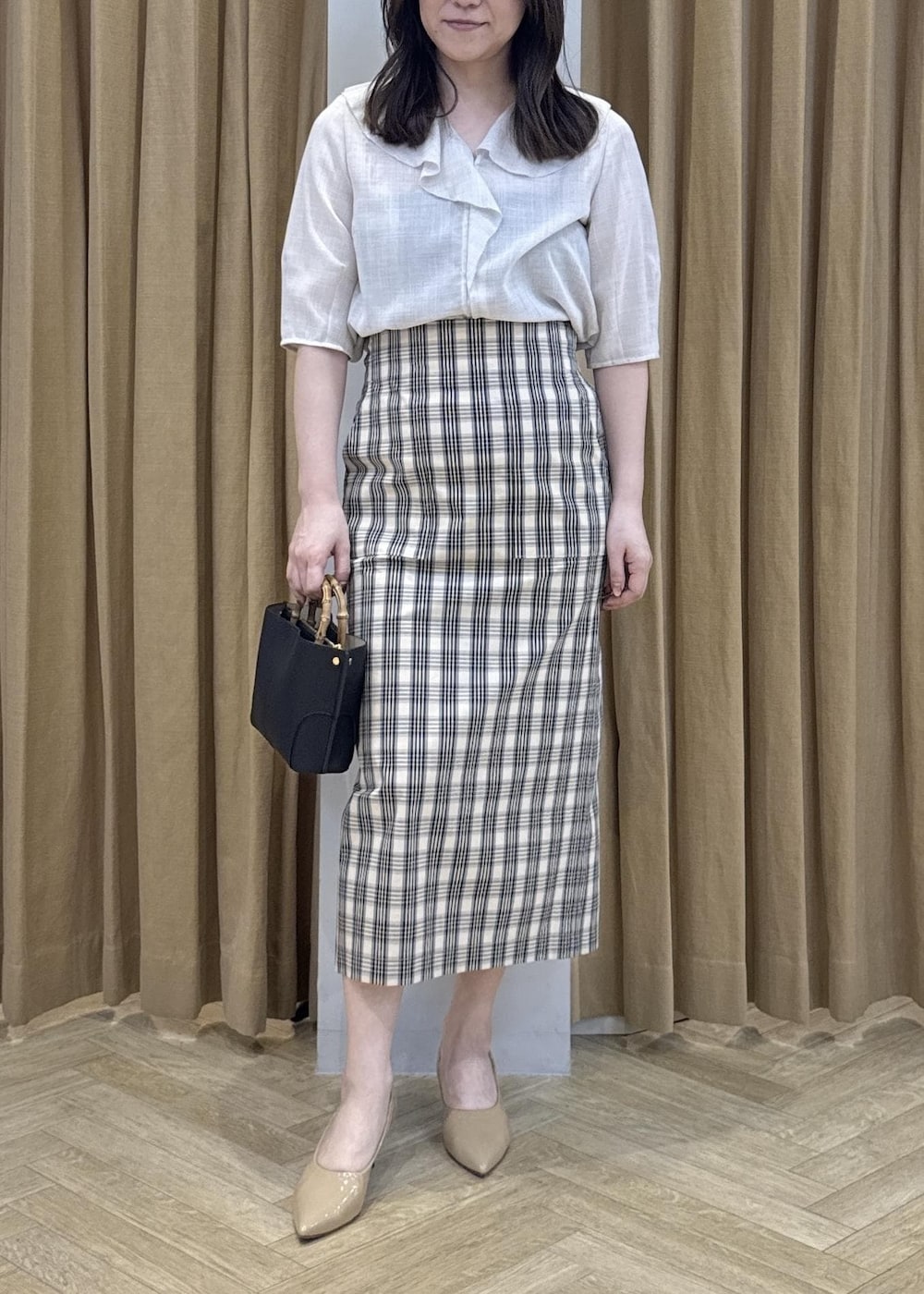 ブラック系のハンドバッグ、ベージュ系のシャツ/ブラウス、ベージュ系のスカートを着用したレディースの春コーディネートの5枚目の写真