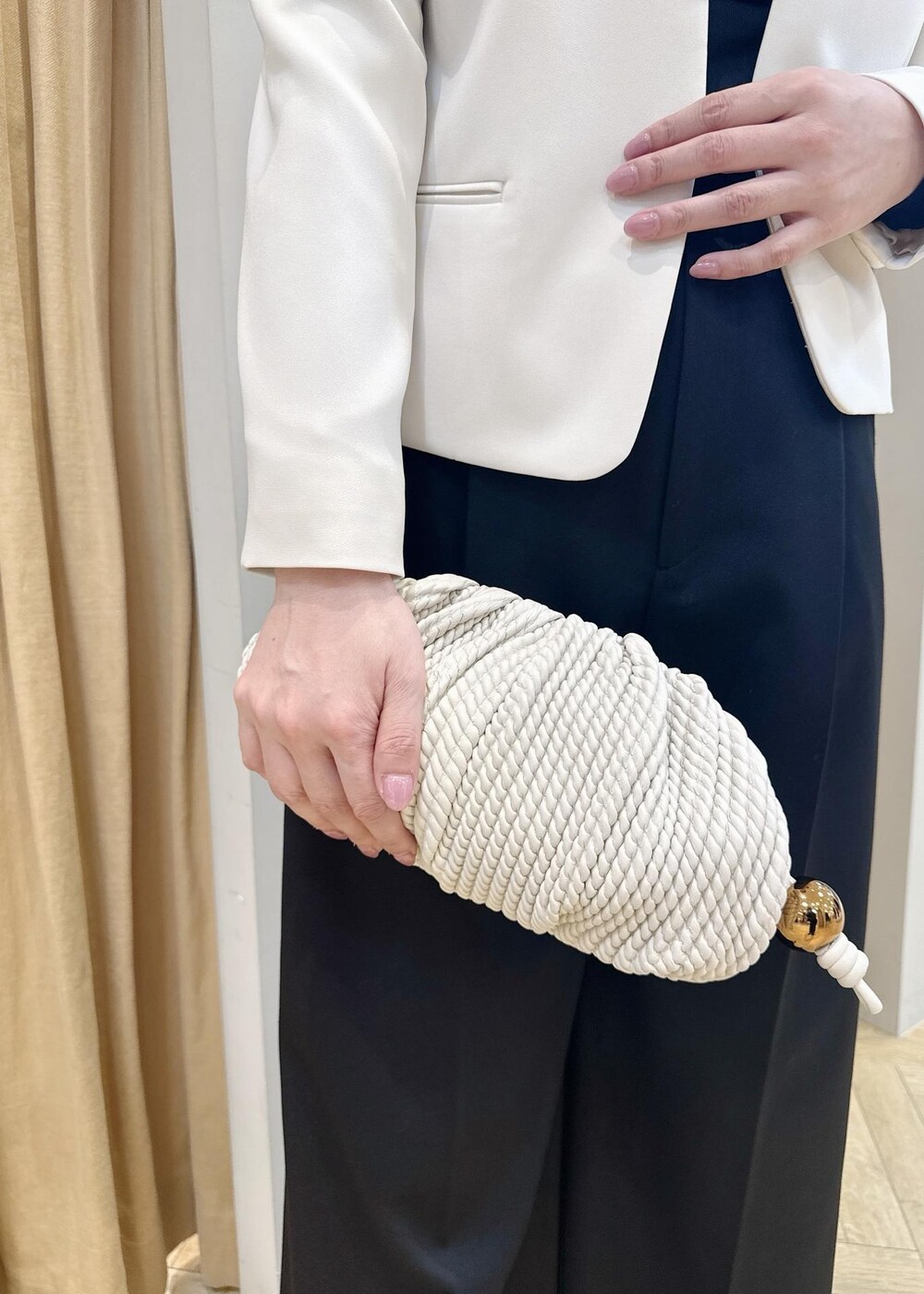 ブラック系のパンプス、ホワイト系のクラッチバッグ、ブラック系のニット/セーターを着用したレディースの冬コーディネートの6枚目の写真