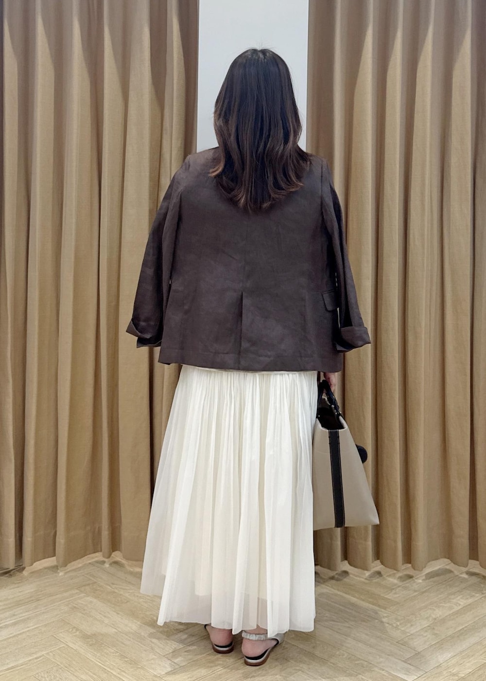 シルバー系のパンプス、ベージュ系のトートバッグ、ブラウン系のノーカラージャケットを着用したレディースの春コーディネートの3枚目の写真