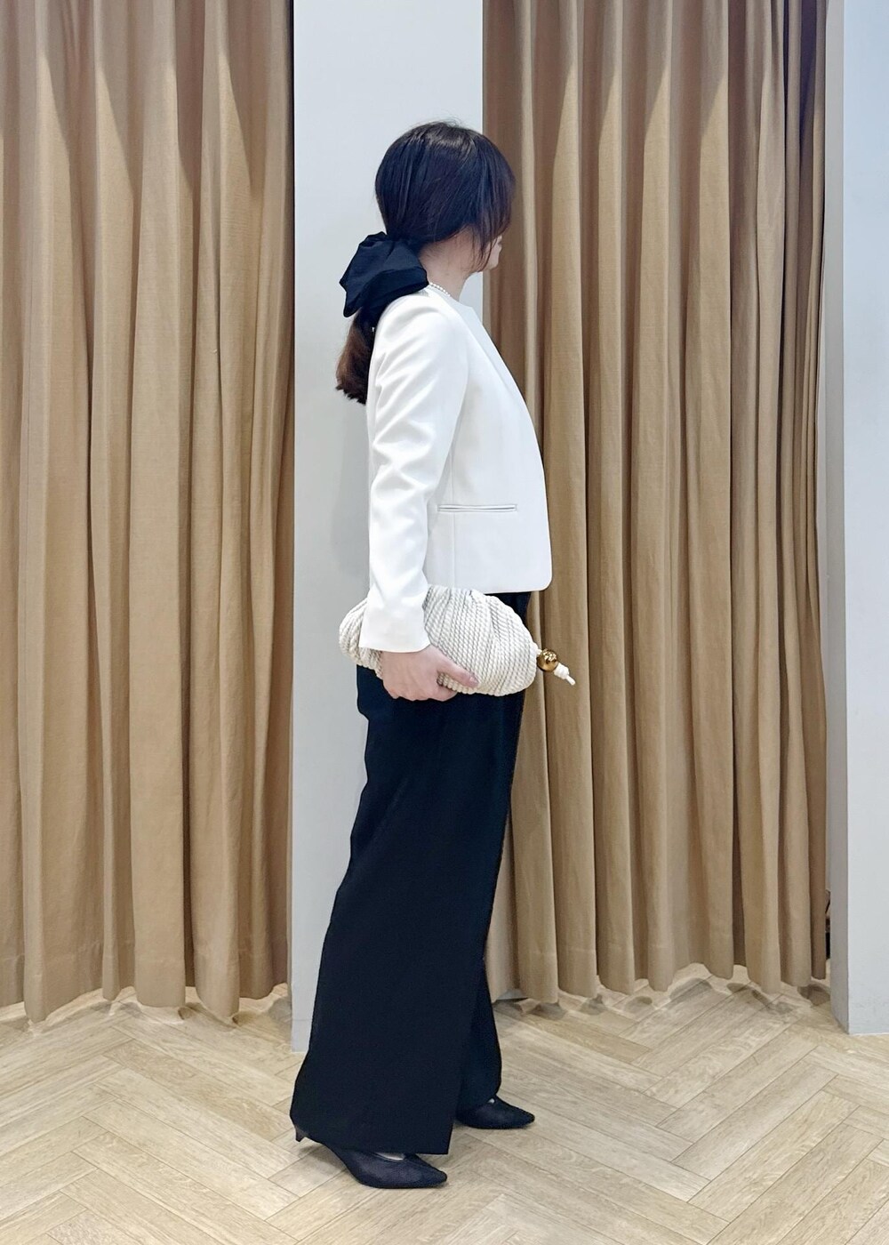 ブラック系のパンプス、ホワイト系のクラッチバッグ、ブラック系のニット/セーターを着用したレディースの冬コーディネートの4枚目の写真