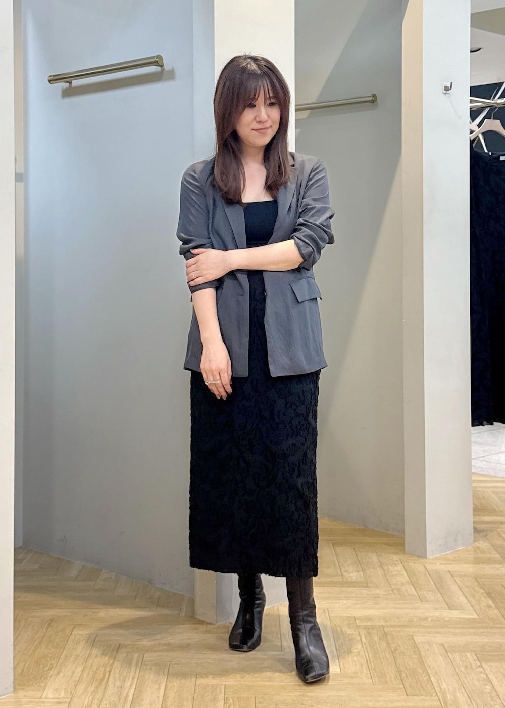 グレー系のテーラードジャケット、ブラック系のスカートを着用したレディースの秋コーディネートの2枚目の写真
