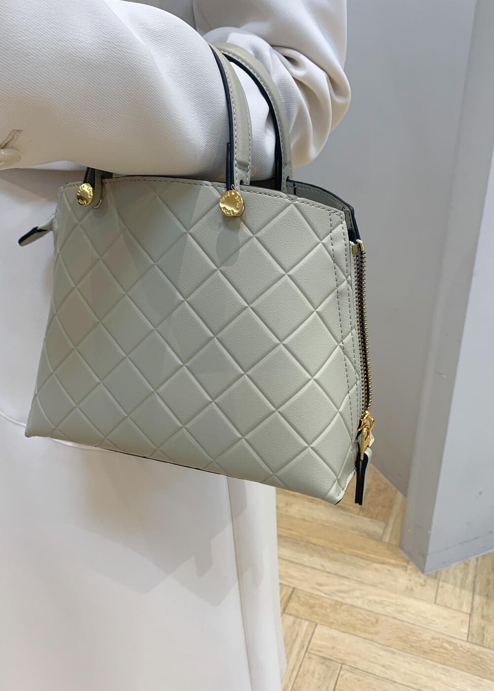 ブラック系のパンプス、ベージュ系のハンドバッグ、ホワイト系のスカートを着用したレディースの冬コーディネートの7枚目の写真