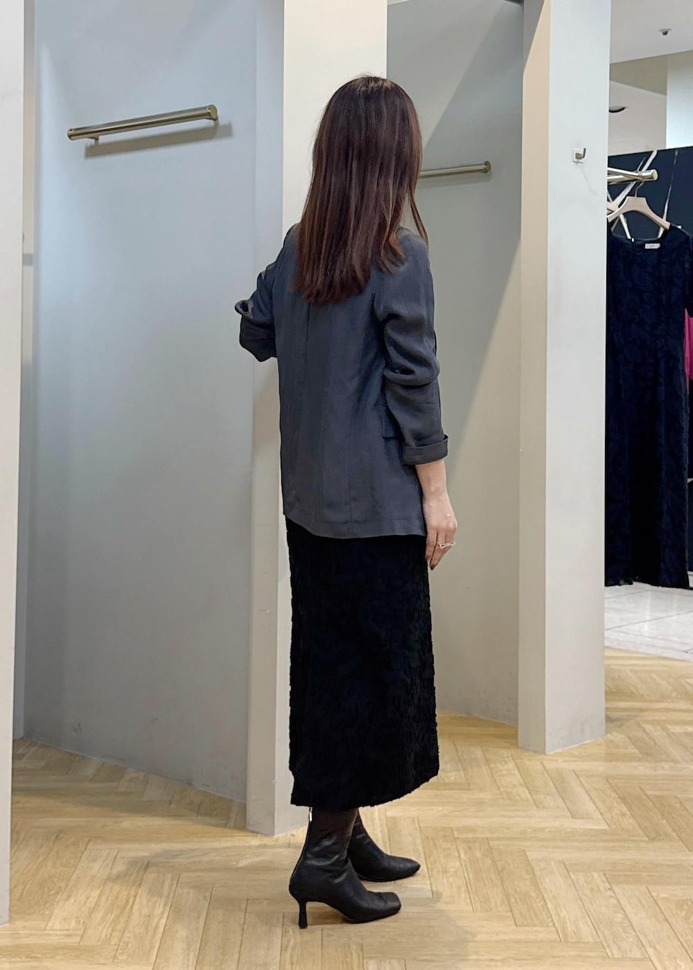 グレー系のテーラードジャケット、ブラック系のスカートを着用したレディースの秋コーディネートの3枚目の写真