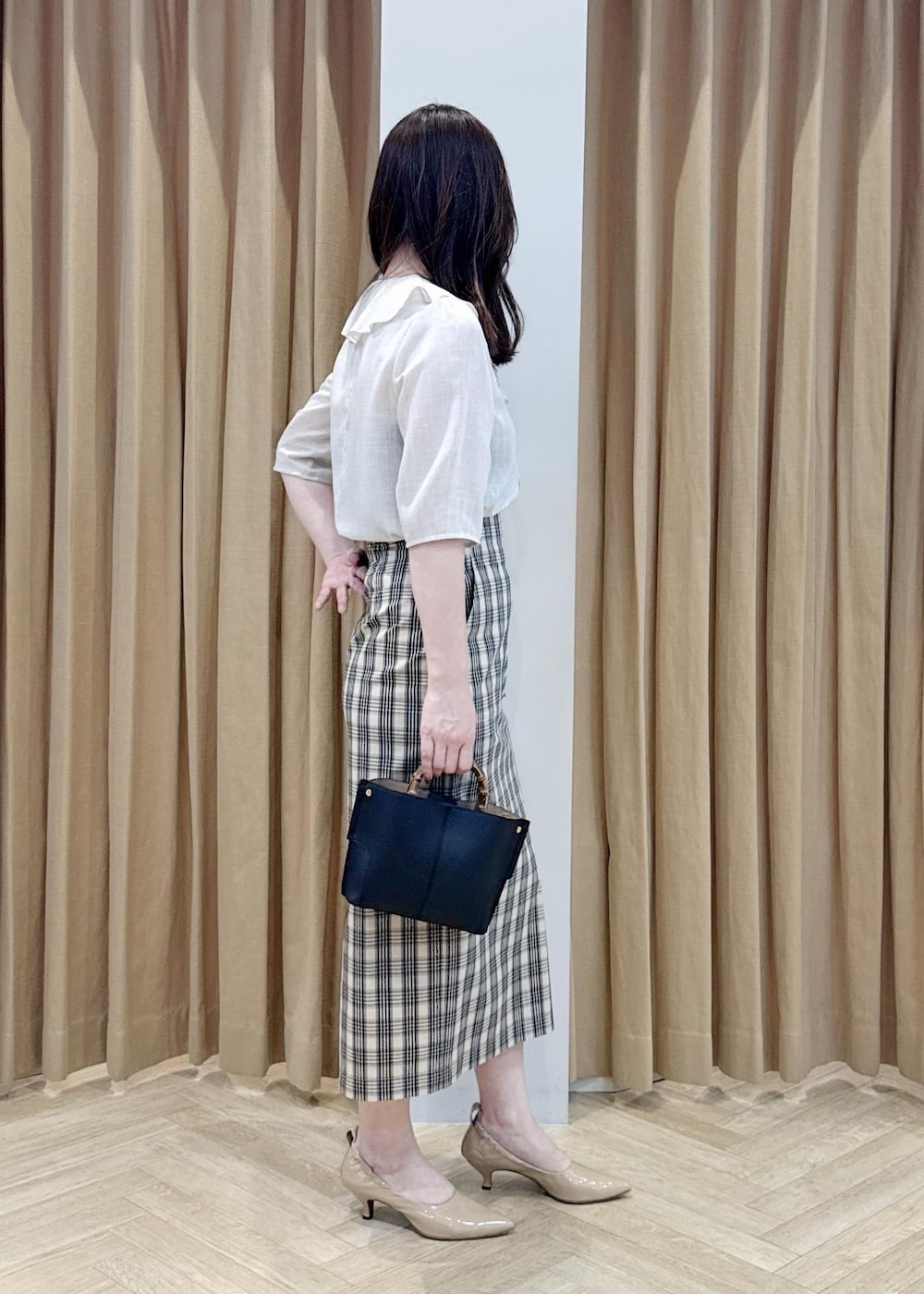 ブラック系のハンドバッグ、ベージュ系のシャツ/ブラウス、ベージュ系のスカートを着用したレディースの春コーディネートの2枚目の写真