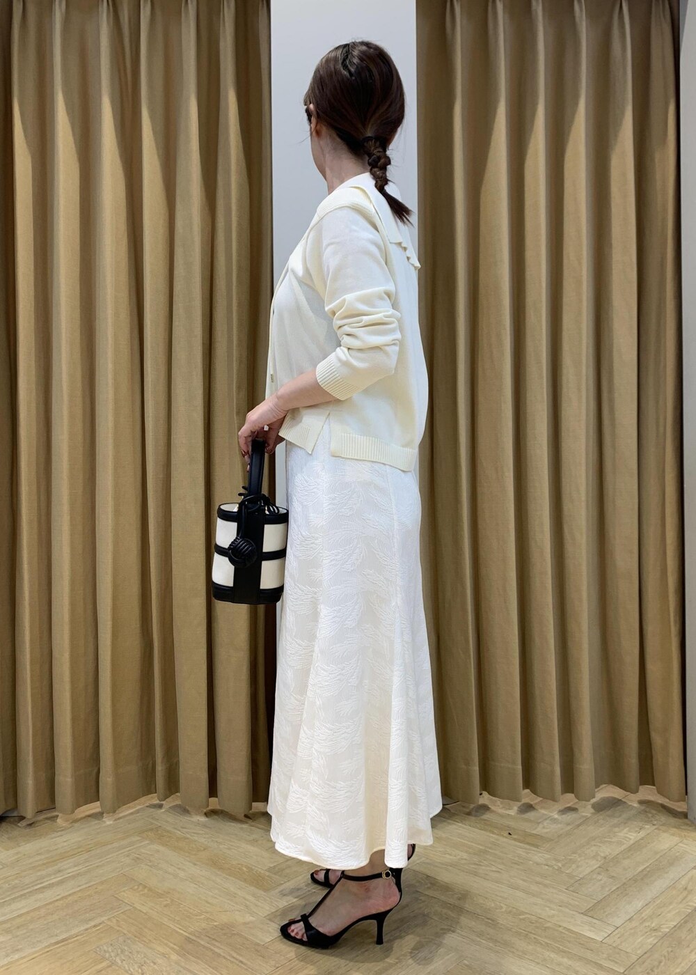 ブラック系のハンドバッグ、ブラック系のサンダル、ホワイト系のニット/セーターを着用したレディースの春コーディネートの3枚目の写真