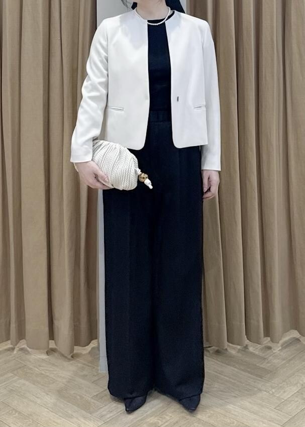 ブラック系のパンプス、ホワイト系のクラッチバッグ、ブラック系のニット/セーターを着用したレディースの冬コーディネートの5枚目の写真