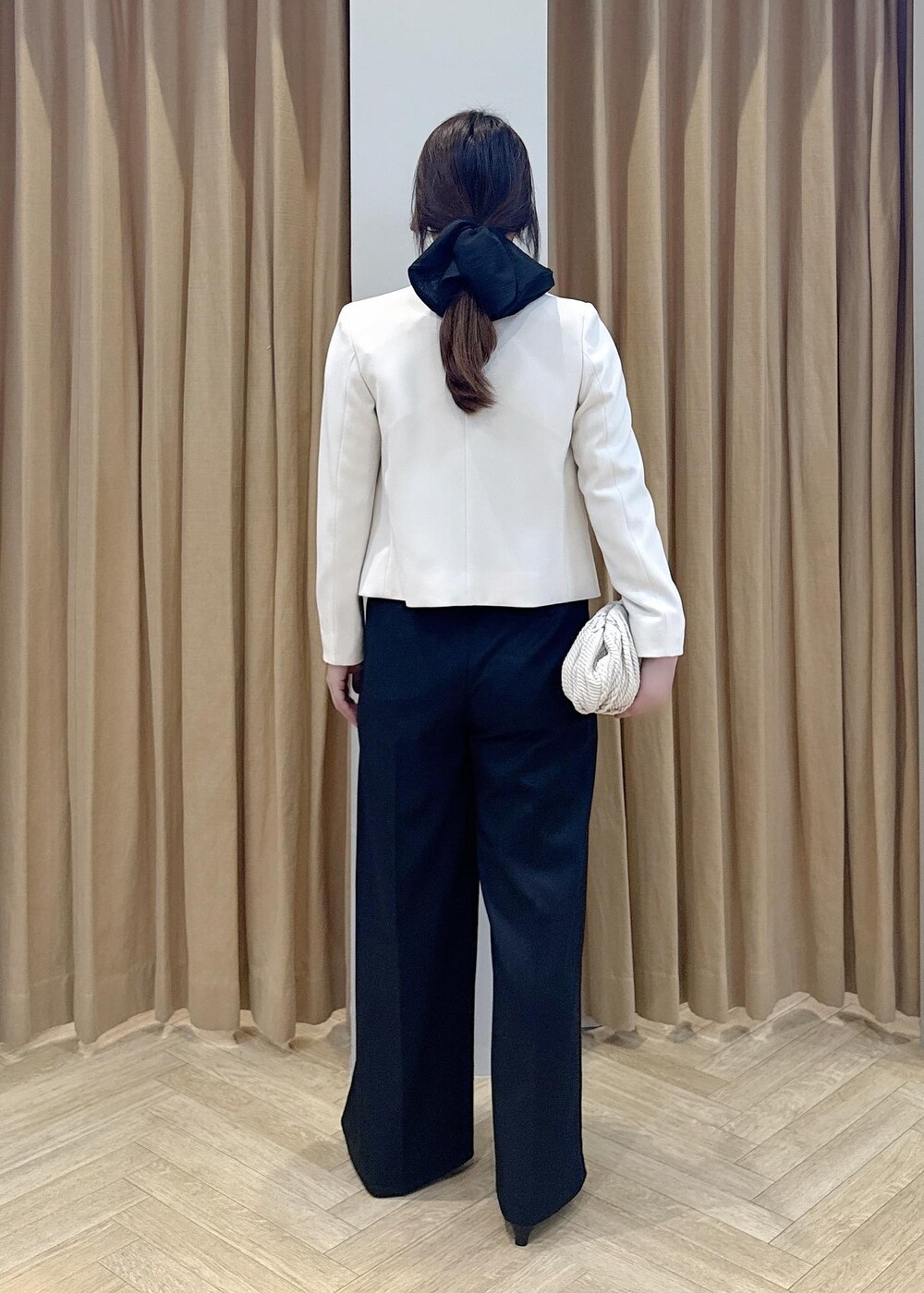 ブラック系のパンプス、ホワイト系のクラッチバッグ、ブラック系のニット/セーターを着用したレディースの冬コーディネートの3枚目の写真