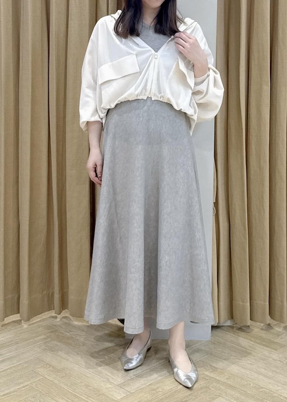 シルバー系のパンプス、ホワイト系のマウンテンパーカー、ベージュ系のワンピースを着用したレディースの春コーディネートの3枚目の写真