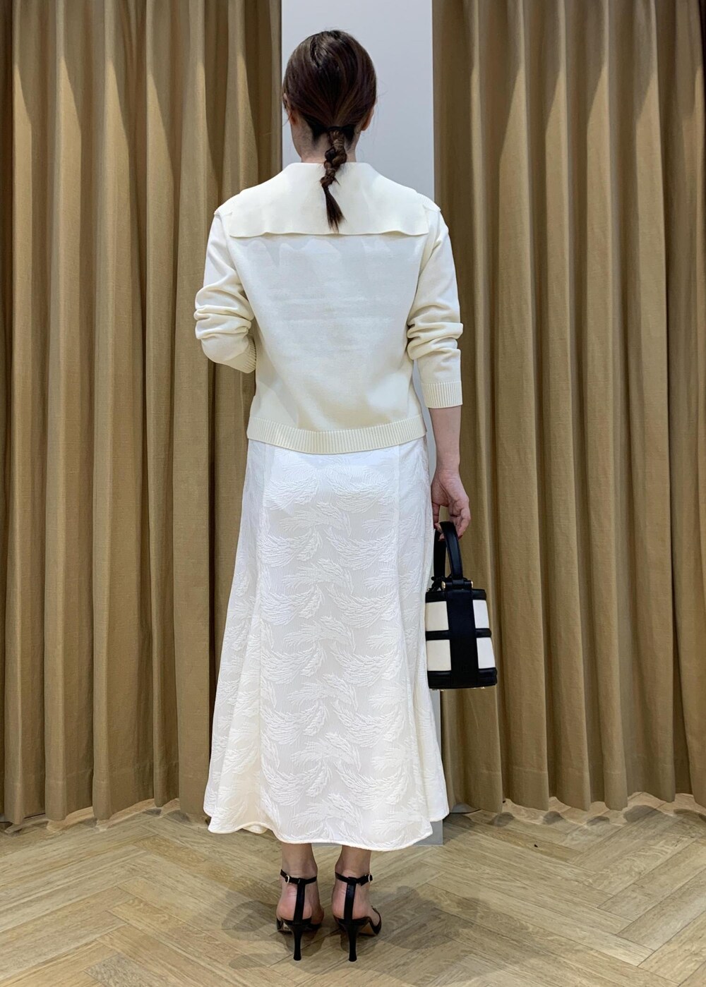 ブラック系のハンドバッグ、ブラック系のサンダル、ホワイト系のニット/セーターを着用したレディースの春コーディネートの4枚目の写真