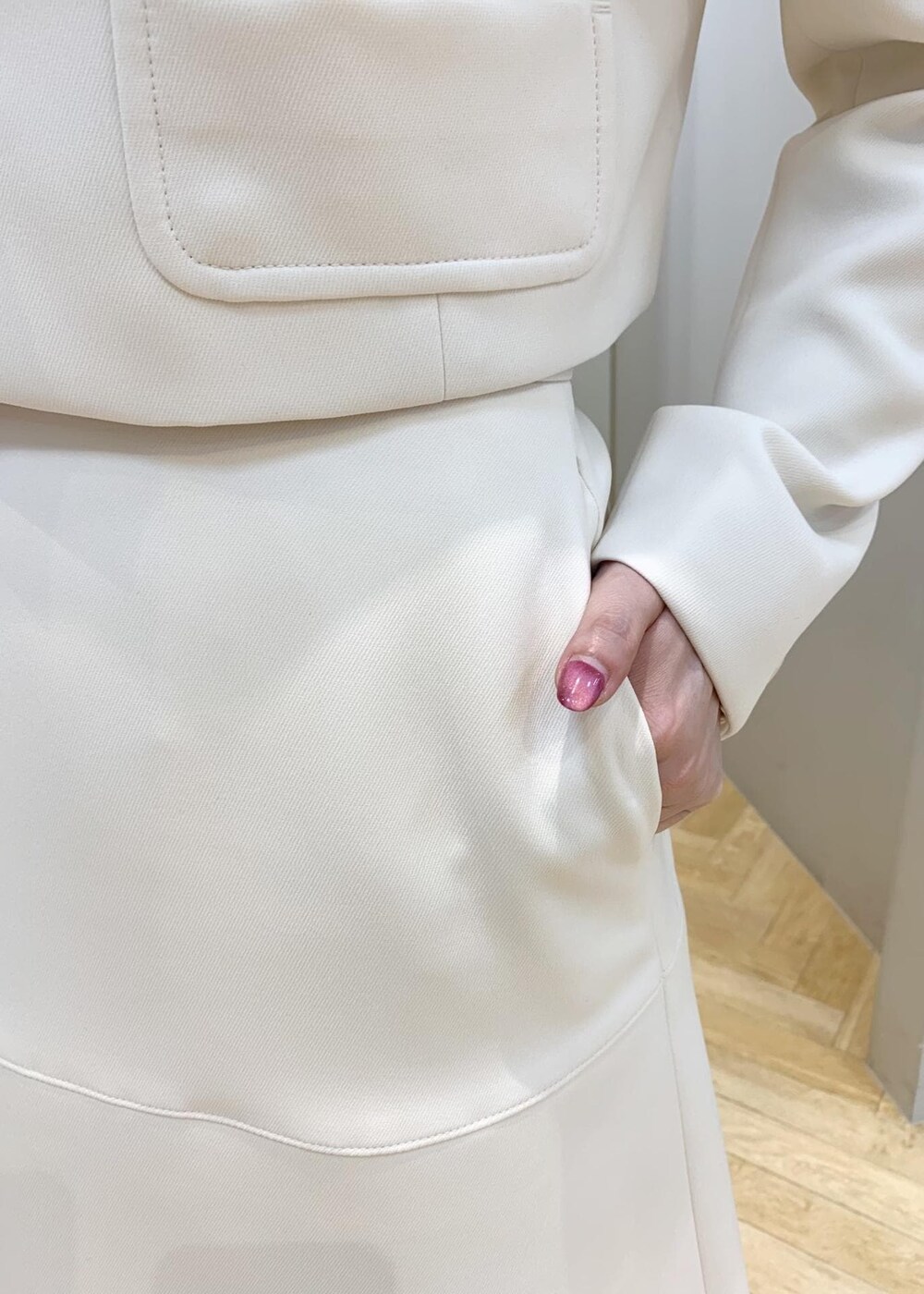 ブラック系のパンプス、ベージュ系のハンドバッグ、ホワイト系のスカートを着用したレディースの冬コーディネートの6枚目の写真