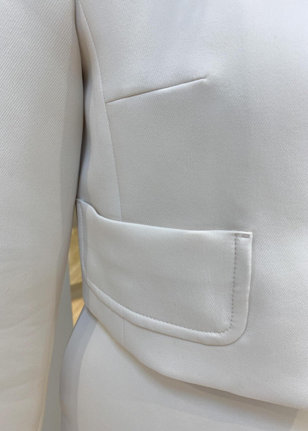 ブラック系のパンプス、ベージュ系のハンドバッグ、ホワイト系のスカートを着用したレディースの冬コーディネートの4枚目の写真