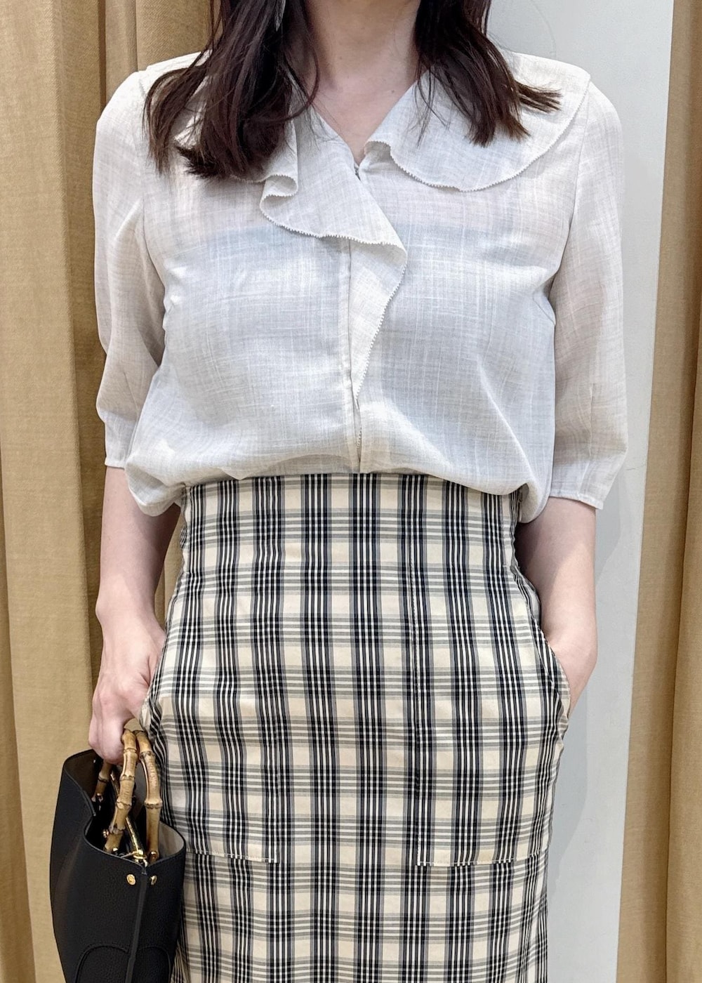 ブラック系のハンドバッグ、ベージュ系のシャツ/ブラウス、ベージュ系のスカートを着用したレディースの春コーディネートの4枚目の写真