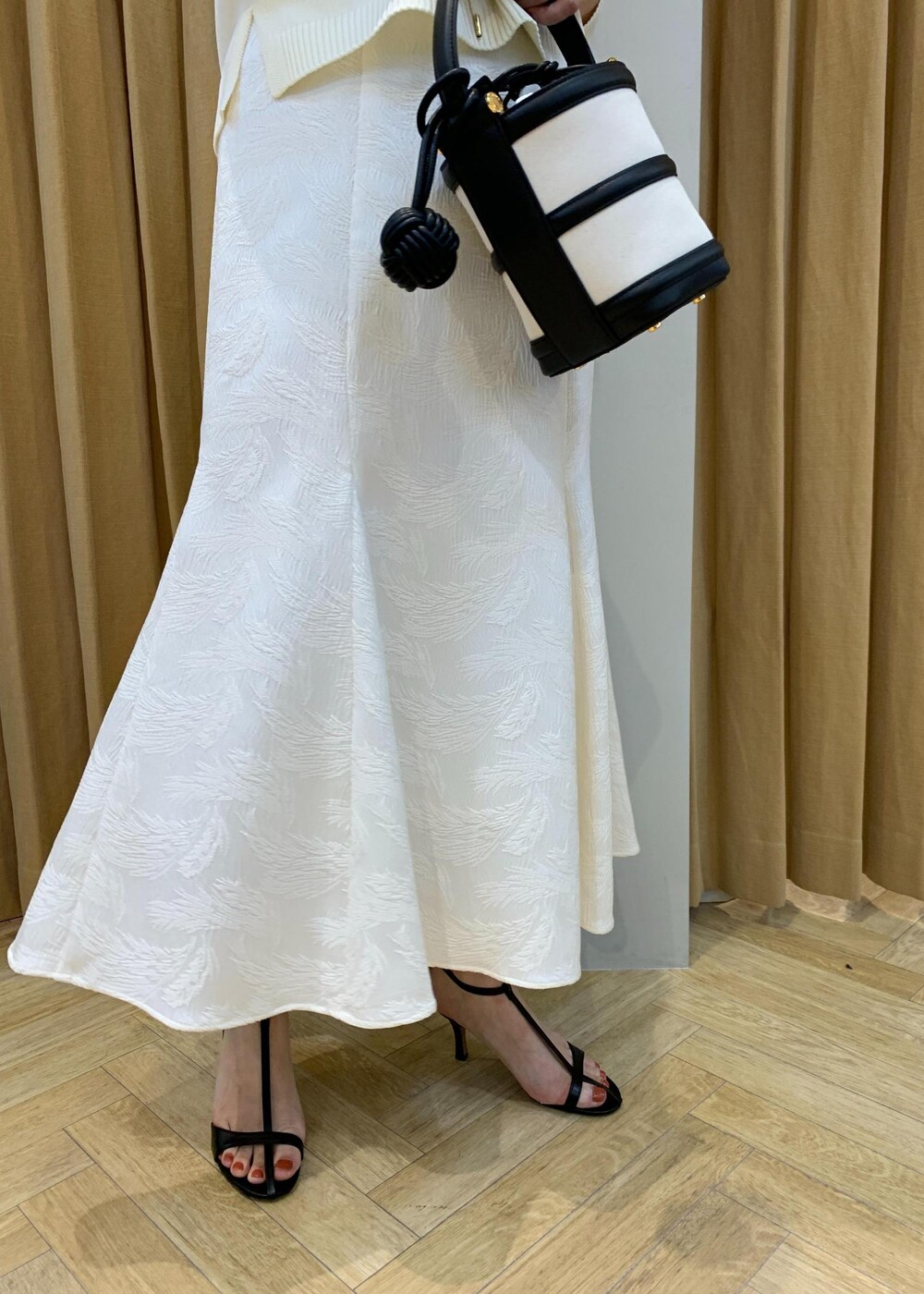 ブラック系のハンドバッグ、ブラック系のサンダル、ホワイト系のニット/セーターを着用したレディースの春コーディネートの5枚目の写真