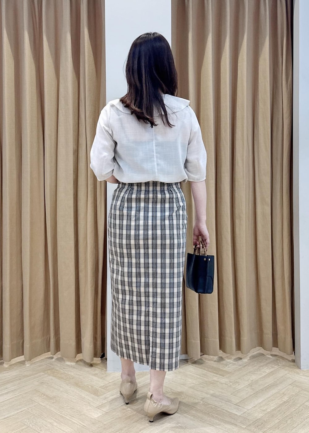 ブラック系のハンドバッグ、ベージュ系のシャツ/ブラウス、ベージュ系のスカートを着用したレディースの春コーディネートの3枚目の写真