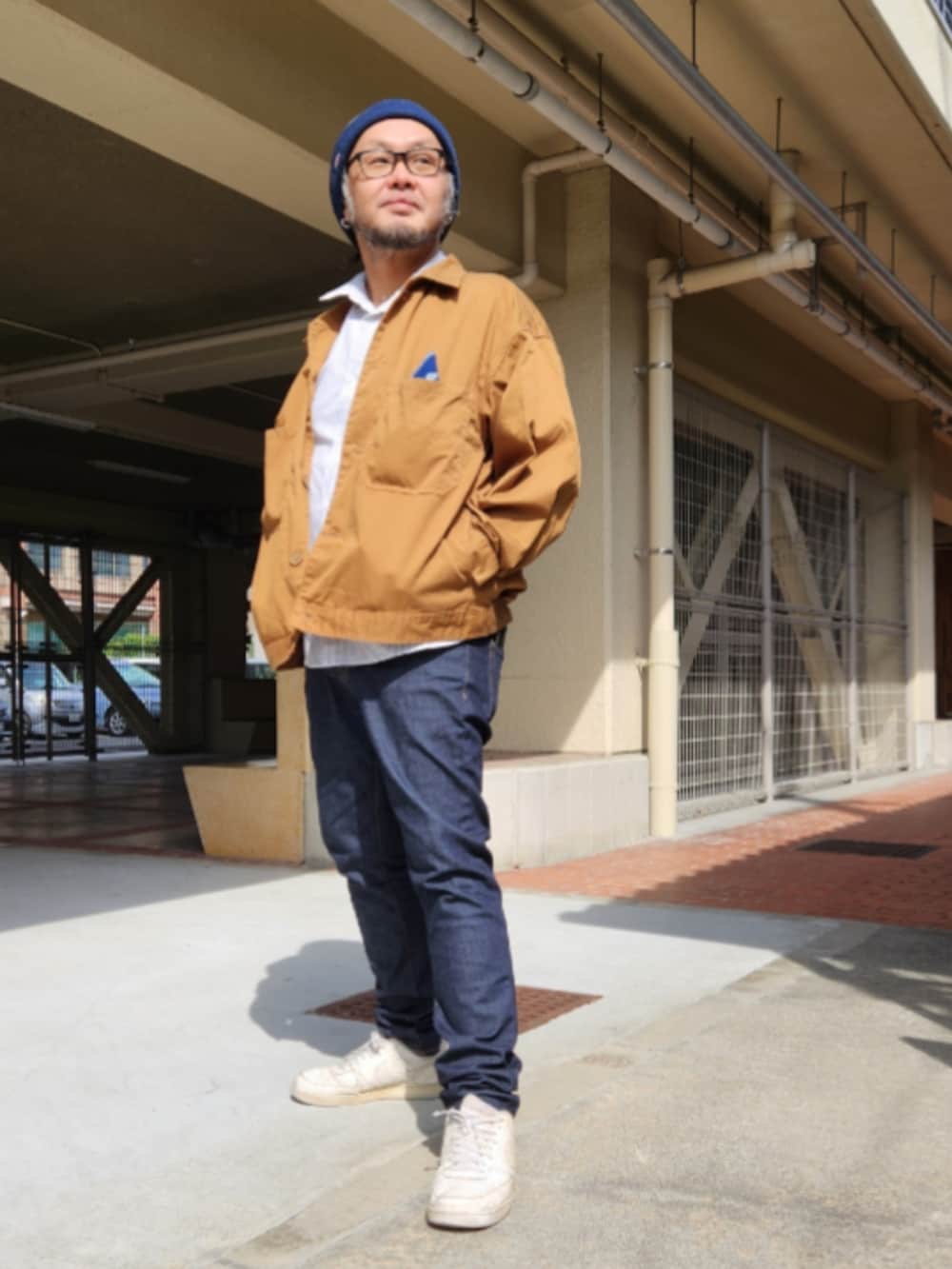 ブルー系のデニムパンツ、ホワイト系のスニーカー、ブラウン系のブルゾンを着用したメンズの春コーディネートの2枚目の写真