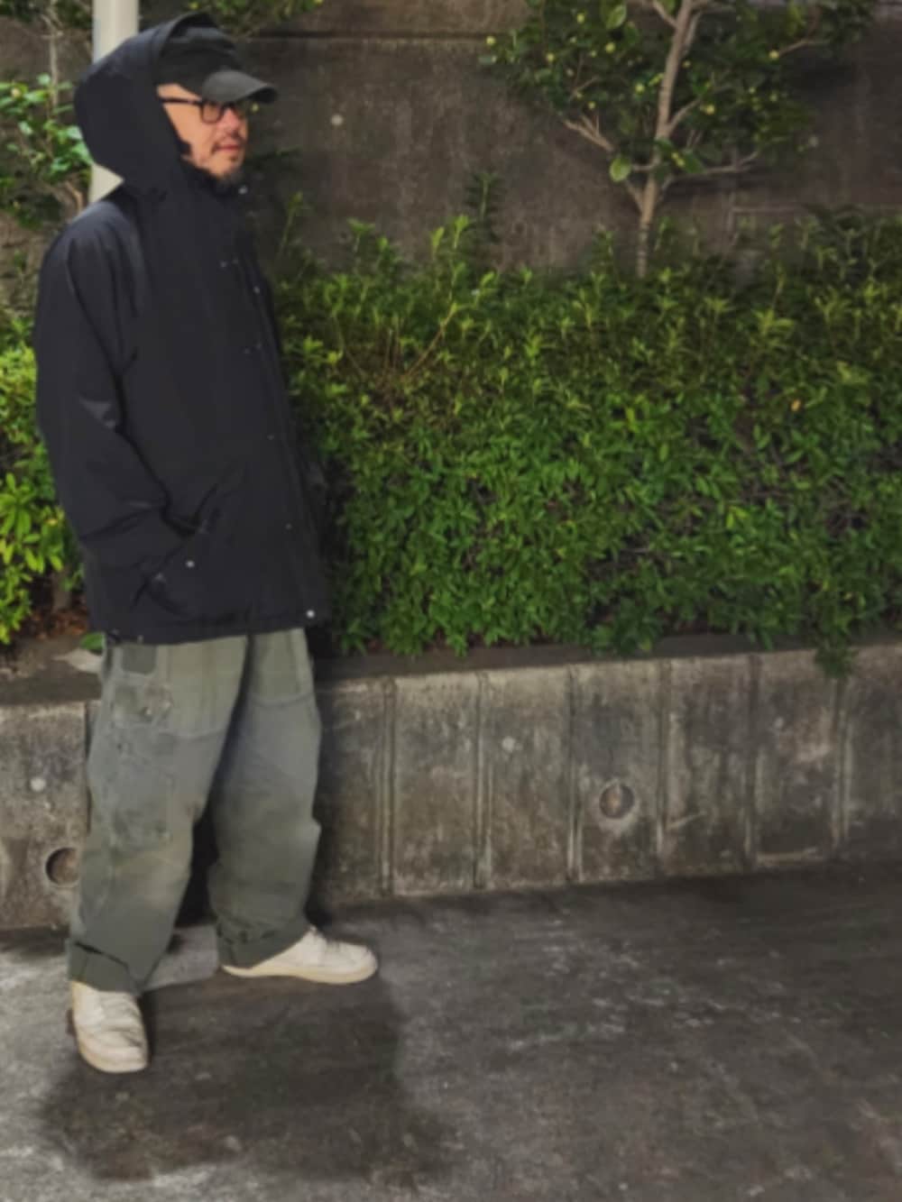 ホワイト系のスニーカー、グリーン系のチノパンツ、ブラック系のナイロンジャケットを着用したメンズの春コーディネートの3枚目の写真