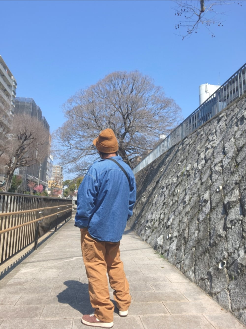 ブラウン系のスニーカー、ブラウン系のカーゴパンツ、ブルー系のショルダーバッグを着用したメンズの春コーディネートの4枚目の写真