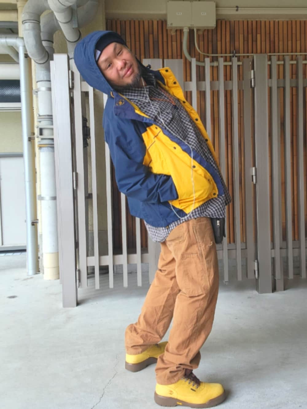 ゴールド系のブーツ、ブラウン系のカーゴパンツ、イエロー系のナイロンジャケットを着用したメンズの春コーディネートの3枚目の写真