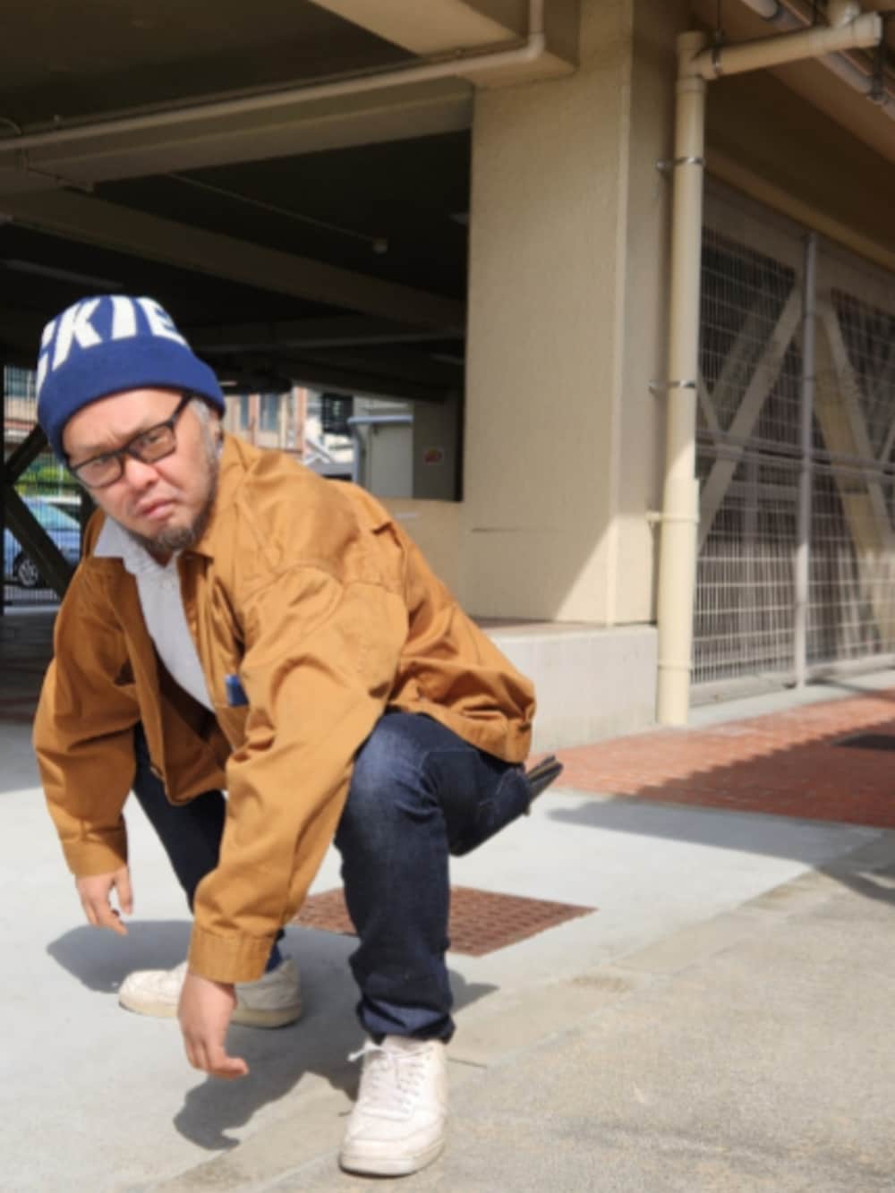 ブルー系のデニムパンツ、ホワイト系のスニーカー、ブラウン系のブルゾンを着用したメンズの春コーディネートの4枚目の写真