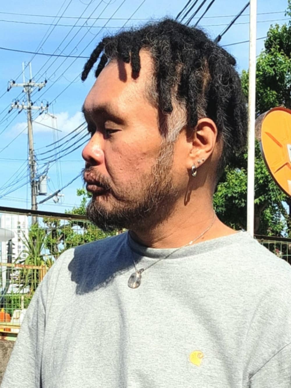 ブラック系のスニーカー、ブラウン系のチノパンツ、グレー系のTシャツ/カットソーを着用したメンズの春コーディネートの4枚目の写真