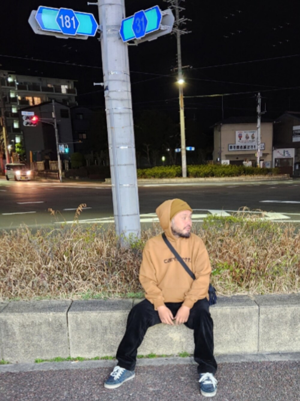ブルー系のスニーカー、ブラック系のスラックス、ブラウン系のパーカーを着用したメンズの春コーディネートの2枚目の写真