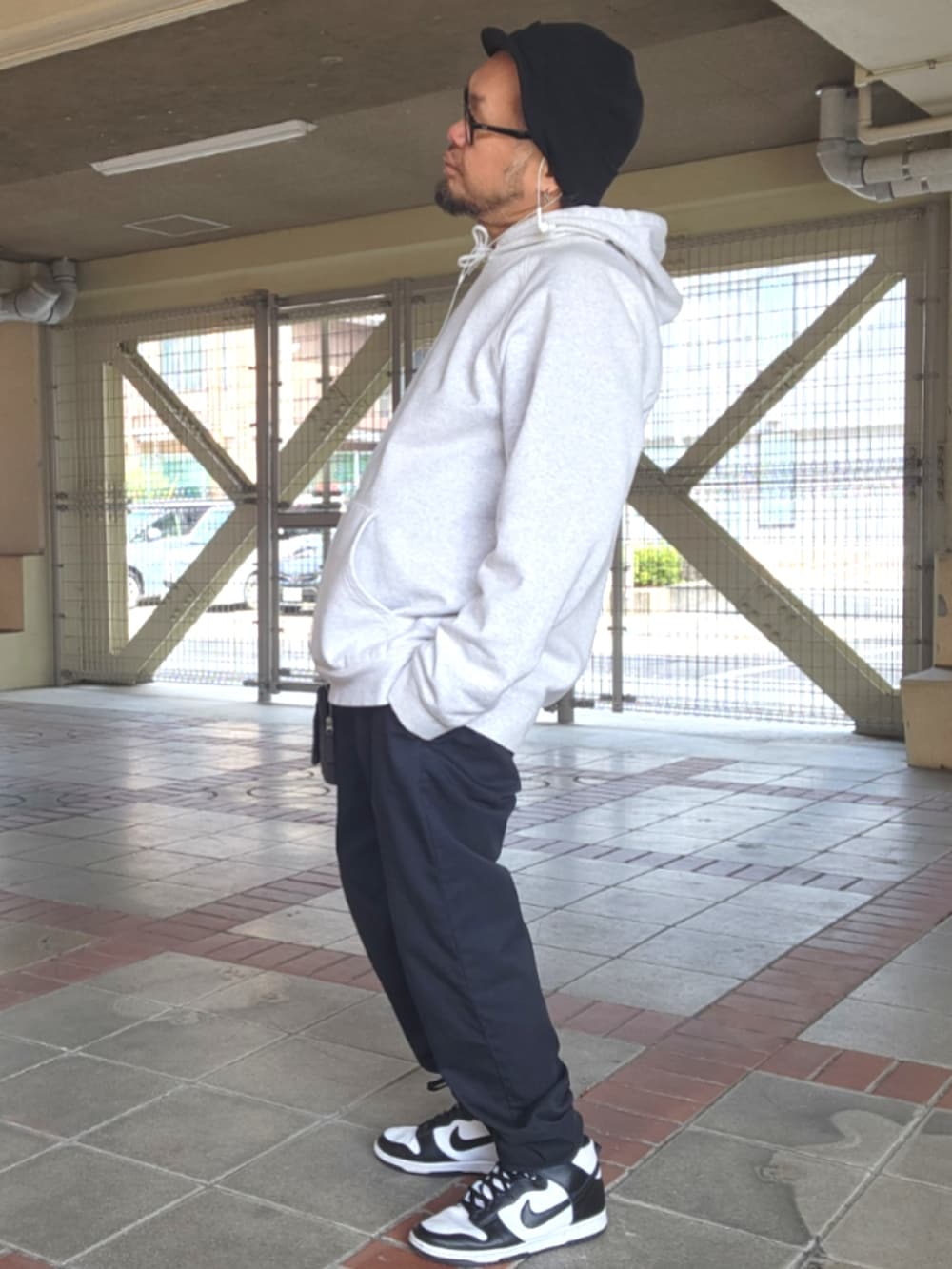 ホワイト系のスニーカー、ブラック系のチノパンツ、グレー系のパーカーを着用したメンズの春コーディネートの2枚目の写真