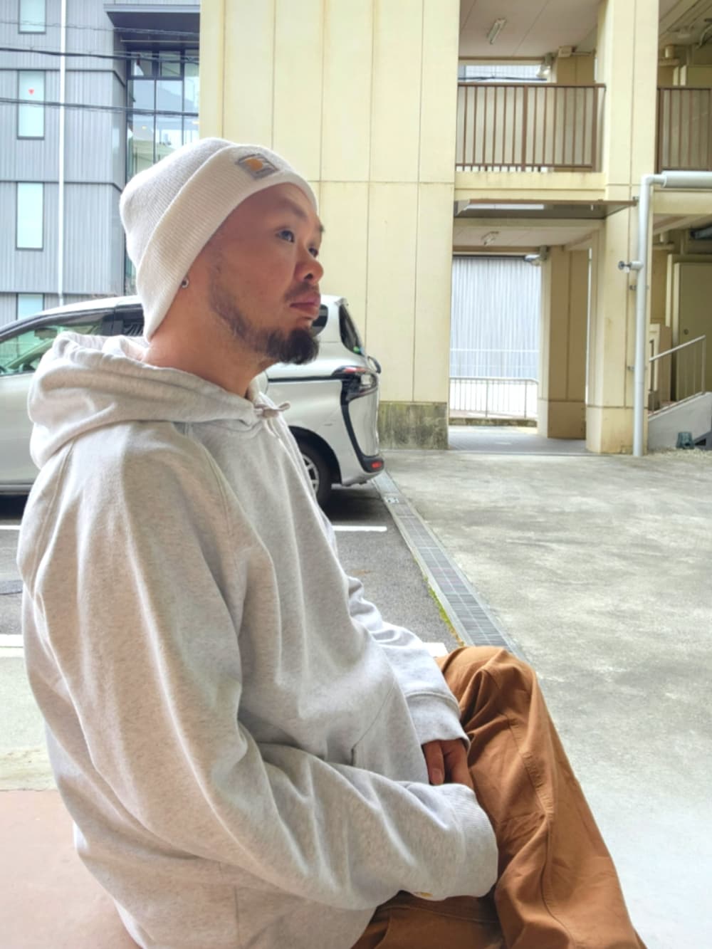 ホワイト系のスニーカー、ブラウン系のカーゴパンツ、グレー系のパーカーを着用したメンズの春コーディネートの5枚目の写真