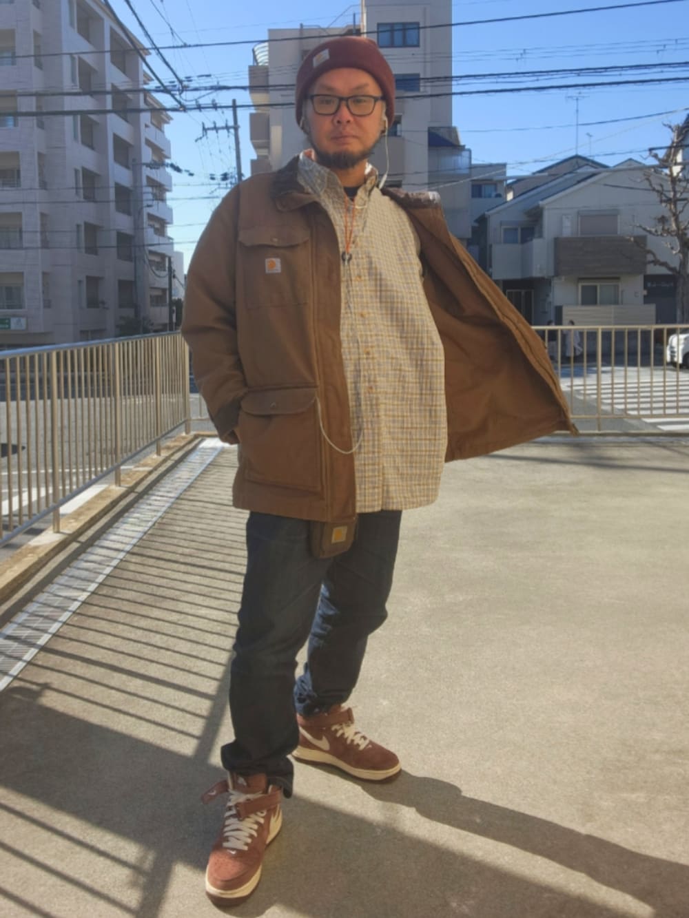 ブラウン系のスニーカー、ブルー系のデニムパンツ、ブラウン系のミリタリージャケットを着用したメンズの春コーディネートの2枚目の写真
