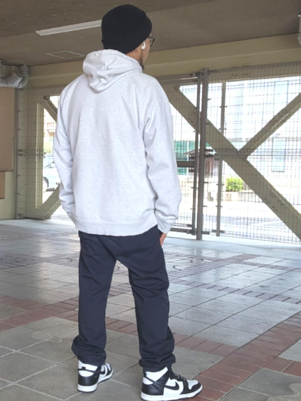 ホワイト系のスニーカー、ブラック系のチノパンツ、グレー系のパーカーを着用したメンズの春コーディネートの3枚目の写真