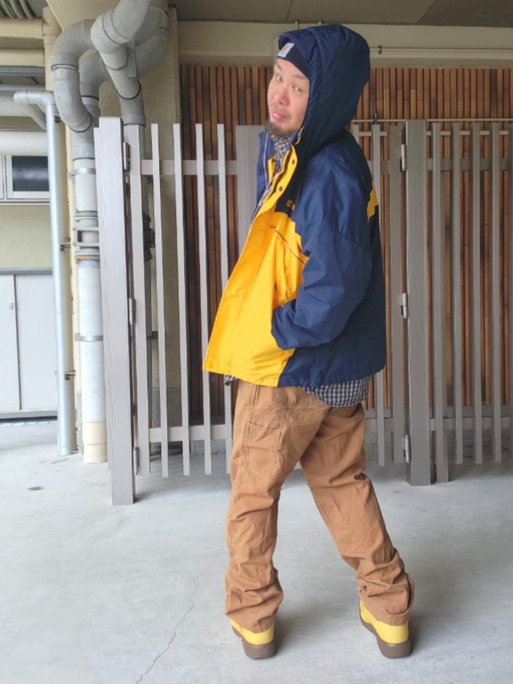 ゴールド系のブーツ、ブラウン系のカーゴパンツ、イエロー系のナイロンジャケットを着用したメンズの春コーディネートの2枚目の写真