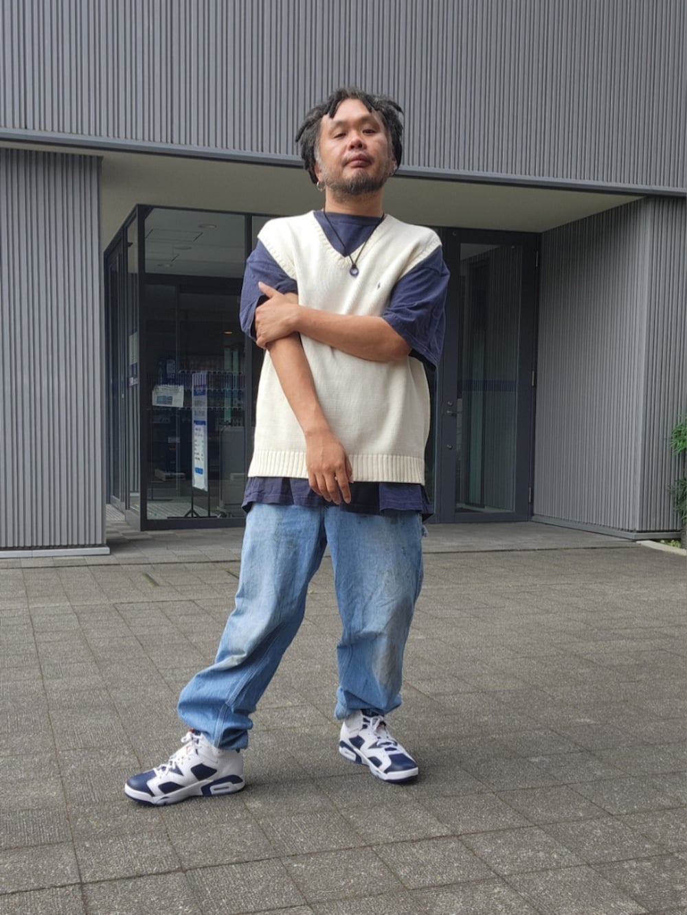 ホワイト系のスニーカー、ブルー系のデニムパンツ、ホワイト系のベストを着用したメンズの夏コーディネートの2枚目の写真