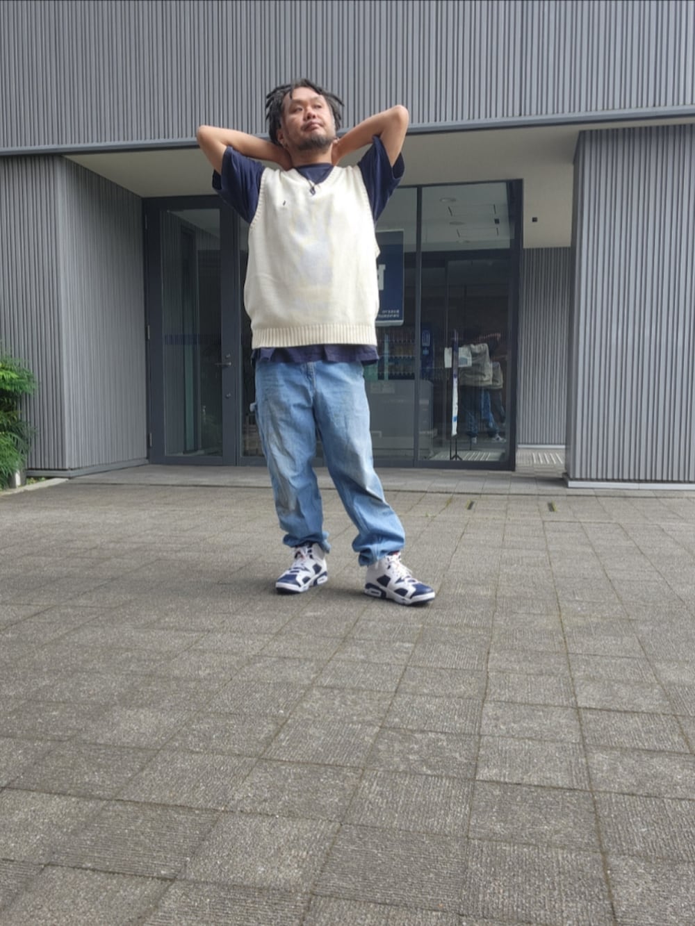 ホワイト系のスニーカー、ブルー系のデニムパンツ、ホワイト系のベストを着用したメンズの夏コーディネートの3枚目の写真