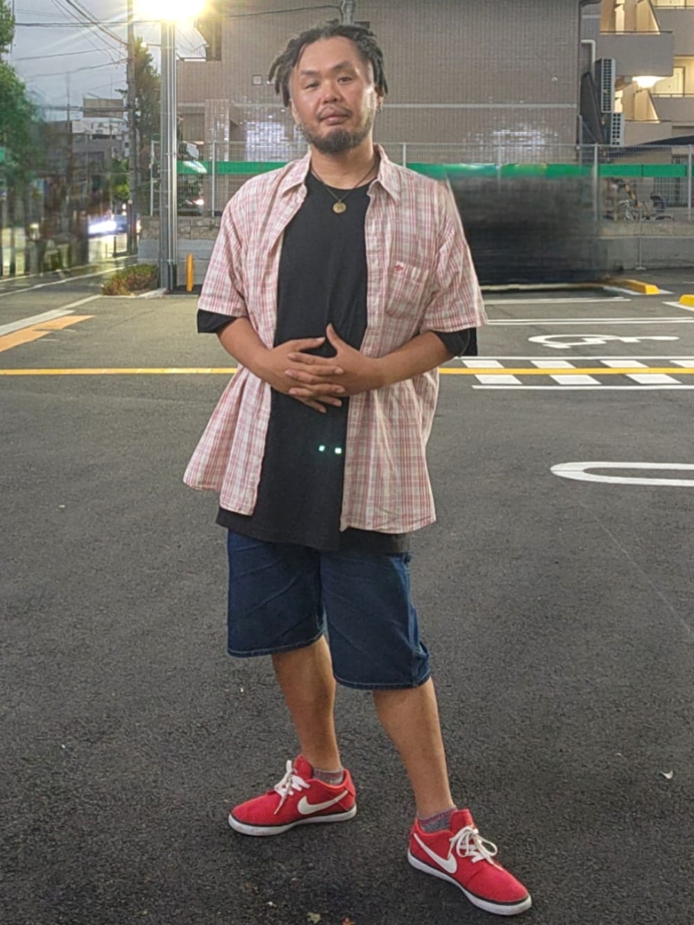 レッド系のスニーカー、ブルー系のデニムパンツ、ブラック系のTシャツ/カットソーを着用したメンズの春コーディネートの3枚目の写真