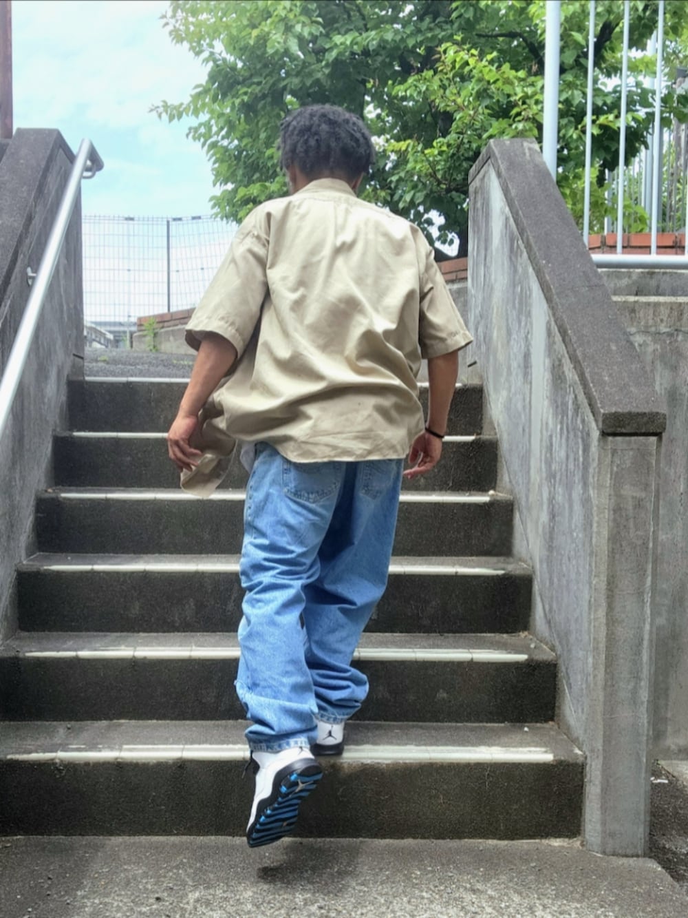 ブルー系のスニーカー、ブルー系のデニムパンツ、ホワイト系のTシャツ/カットソーを着用したメンズの夏コーディネートの2枚目の写真