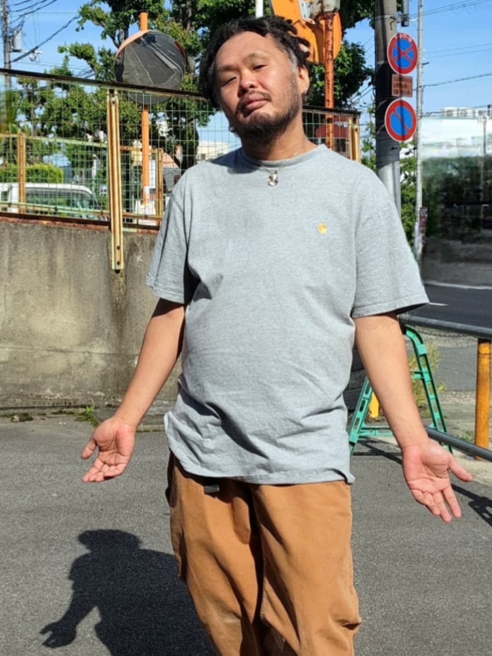 ブラック系のスニーカー、ブラウン系のチノパンツ、グレー系のTシャツ/カットソーを着用したメンズの春コーディネートの5枚目の写真