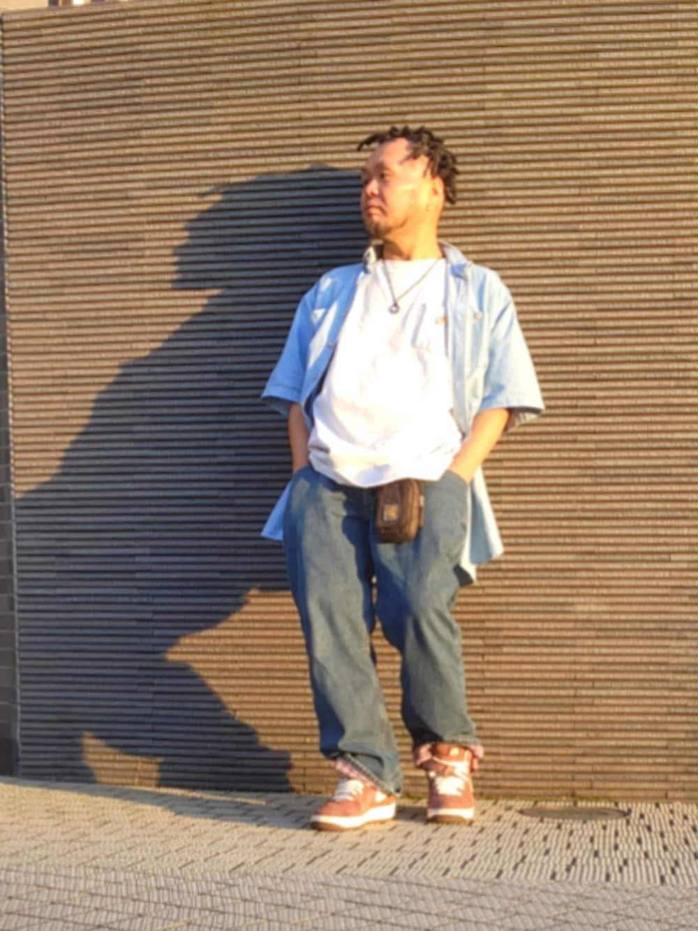 ブラウン系のスニーカー、ブルー系のデニムパンツ、ホワイト系のTシャツ/カットソーを着用したメンズの春コーディネートの2枚目の写真