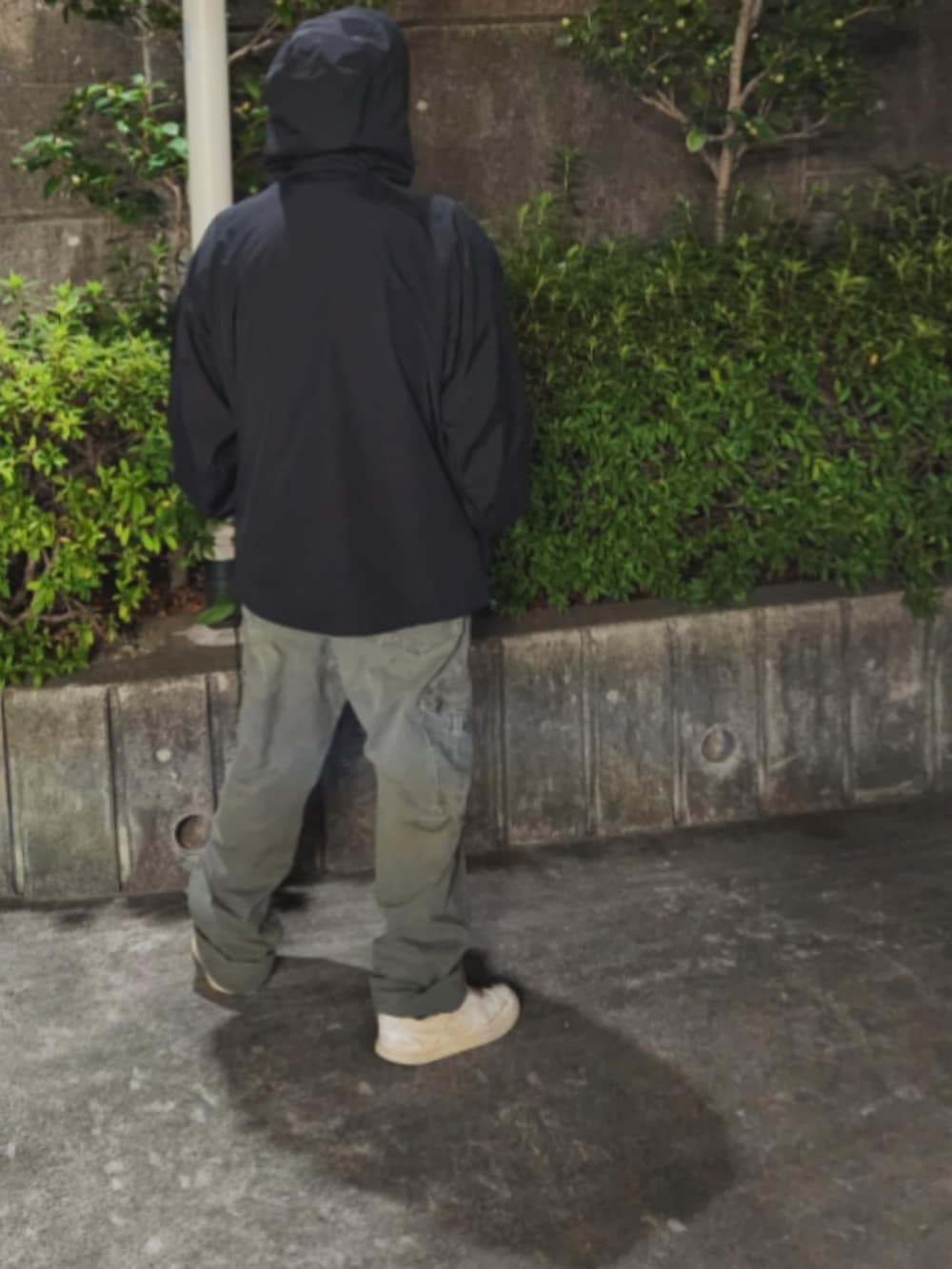 ホワイト系のスニーカー、グリーン系のチノパンツ、ブラック系のナイロンジャケットを着用したメンズの春コーディネートの4枚目の写真