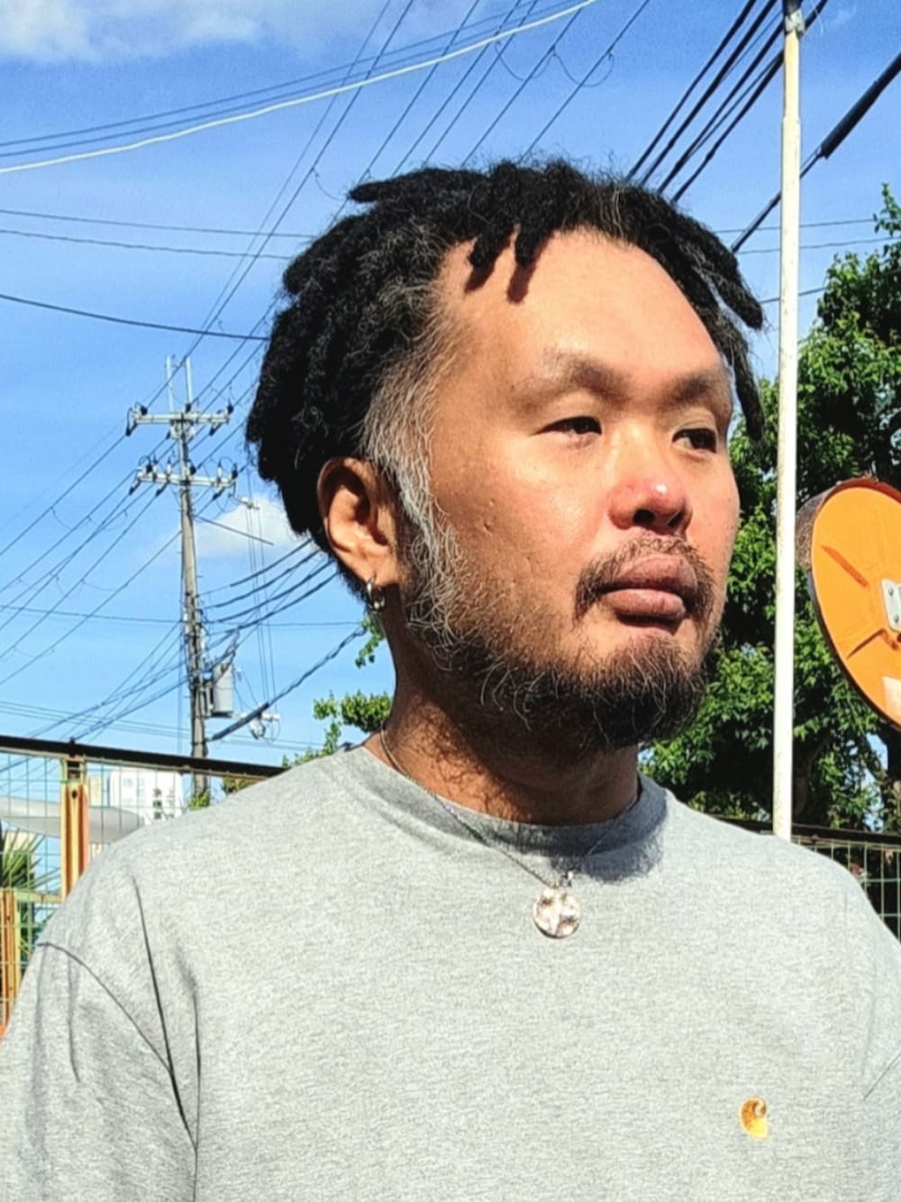ブラック系のスニーカー、ブラウン系のチノパンツ、グレー系のTシャツ/カットソーを着用したメンズの春コーディネートの3枚目の写真